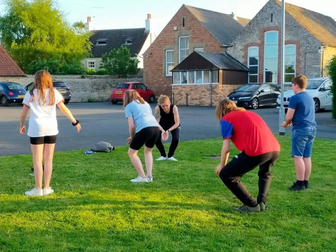 Youth group Qigong class, on lush green grass as the sun is setting. 
