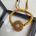 Five Emperor Coins Earth Yellow Cord Bracelet handmade with traditional Vajra Knot, adjustable Chinese Feng Shui jewelry for protection.
