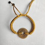 Five Emperor Coins Earth Yellow Cord Bracelet handmade with traditional Vajra Knot, adjustable Chinese Feng Shui jewelry for protection.